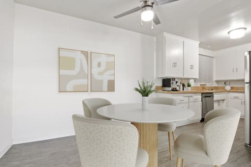 a kitchen with white cabinets and a white table and chairs