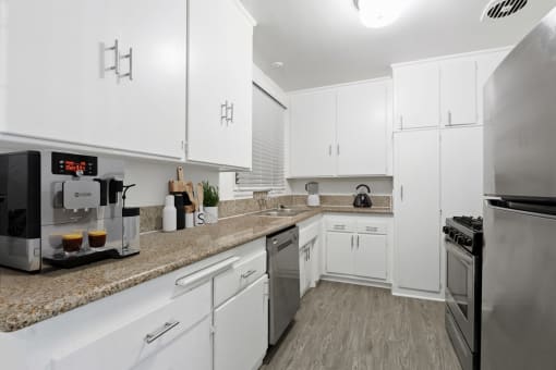 a kitchen with white cabinets and granite counter tops and stainless steel appliances