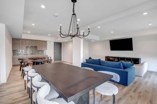 a large wooden table with white chairs and a blue couch in a room with white walls and