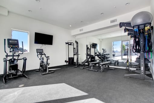 a spacious fitness room with cardio equipment and a flat screen tv