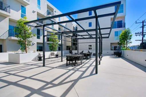 a patio with tables and chairs in front of an apartment building