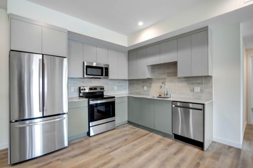 a kitchen with gray cabinets and stainless steel appliances