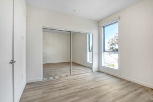 a bedroom with hardwood floors and white walls