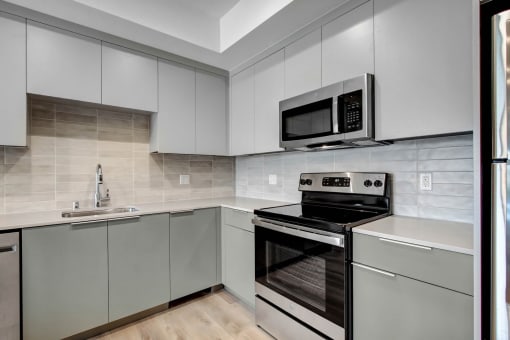 a kitchen with gray cabinets and stainless steel appliances