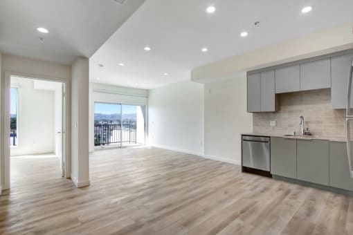 a kitchen and living room with white walls and hardwood floors