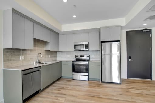 a kitchen with gray cabinets and stainless steel appliances