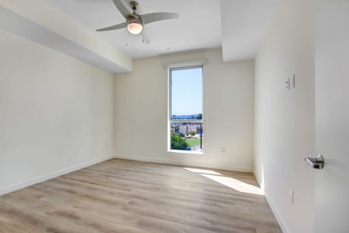 a bedroom with a large window and hardwood floors