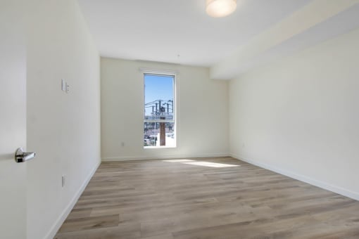 a bedroom with hardwood floors and white walls