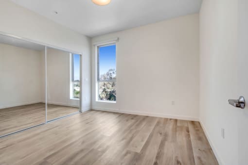 a bedroom with hardwood floors and white walls