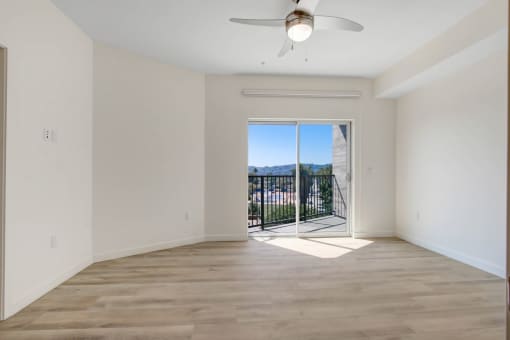 an empty living room with a sliding glass door leading to a balcony