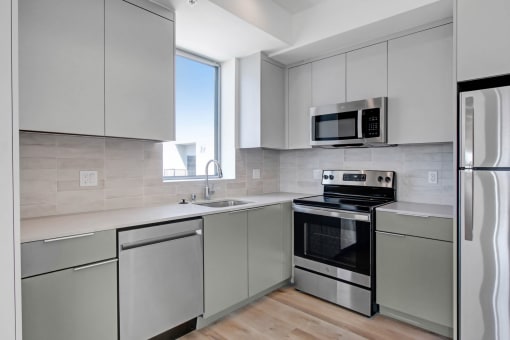 a kitchen with gray cabinets and stainless steel appliances
