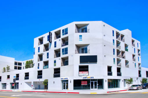 a white apartment building with balconies and a red and white sign on the side of the