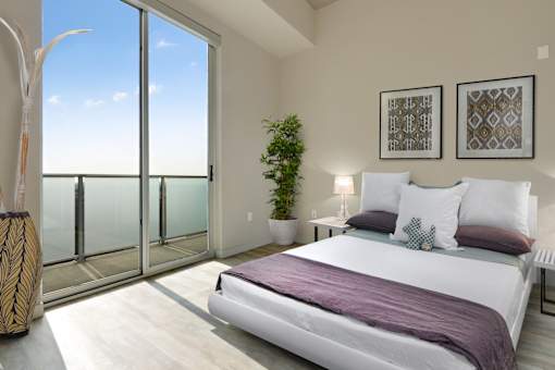 A bedroom with a large bed and a view of the sky through the window.