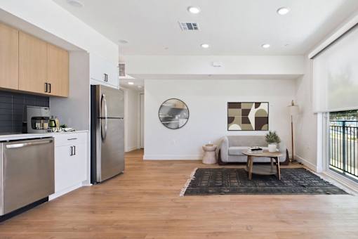 A modern kitchen with wooden floors and stainless steel appliances.