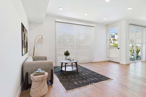 A living room with a chair, ottoman, and table.