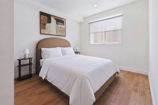 A bedroom with a large bed and a painting on the wall.
