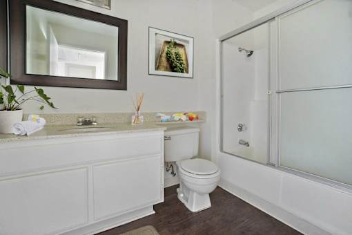 A white toilet sits in a bathroom next to a sink and a shower.