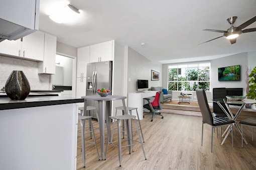 Dining area with ceiling fan, cozy fireplace in the den and living room, wood-like floors throughout