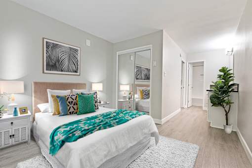 Bedroom with mirrored closet doors and a vanity area with wood-inspired floors throughout