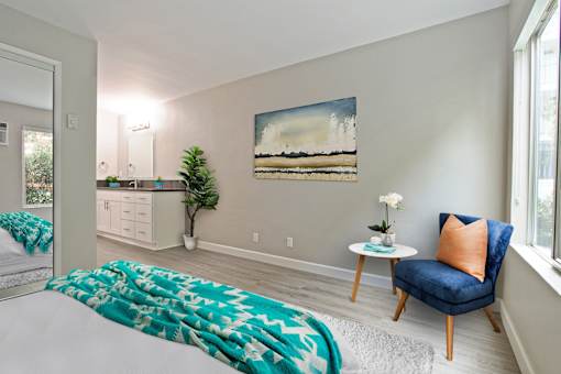 Bedroom with wood-inspired floors, mirrored closet doors and a vanity area on the left