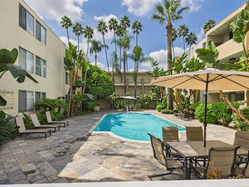 A pool surrounded by chairs and trees.