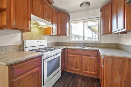 Kitchen with white gas stove, granite countertops, wood style kitchen cabinets