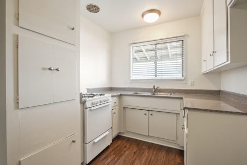 Kitchen with white gas stove, granite countertops, White kitchen cabinets