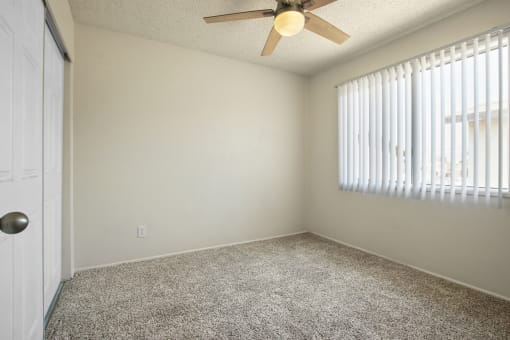 Bedroom with sliding closet door at the left, ceiling fan, carpeted flooring