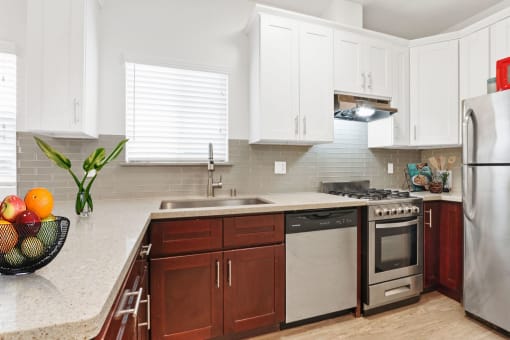 a kitchen with white cabinets and a bowl of fruit on the counter