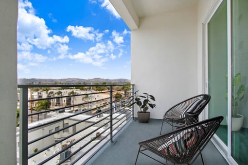 a balcony with two chairs and a plant