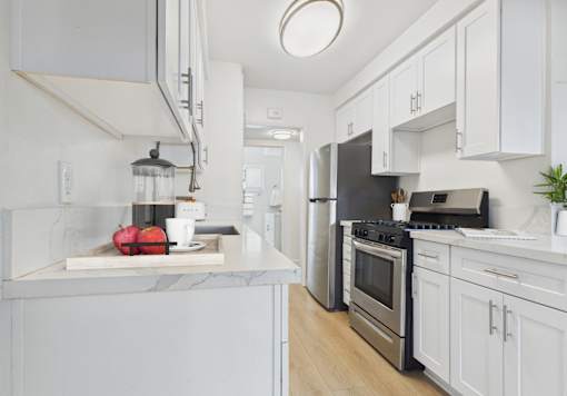 A kitchen with white cabinets and a marble countertop.