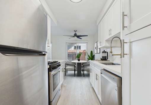 A modern kitchen with white cabinets and stainless steel appliances.