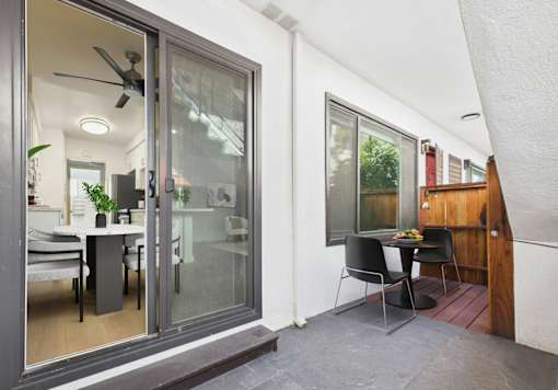 A modern patio with a glass door leading to a dining area.