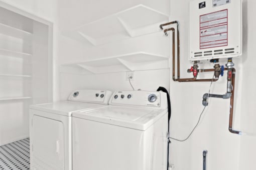 a white laundry room with two washers and a dryer