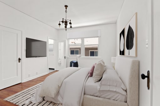 a white bedroom with a bed and a tv