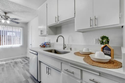 a white kitchen with white cabinets and a stainless steel sink