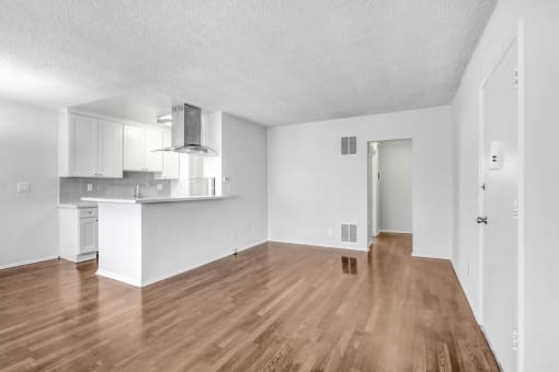 the living room and kitchen of an apartment with wood flooring