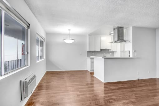 an empty living room and kitchen with a large window