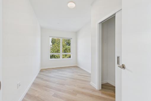 A room with a door and a window with a view of trees.