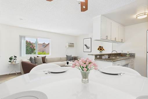 A white dining table with a vase of pink flowers on it.