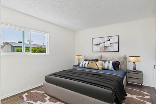 A bedroom with a large bed and a window overlooking a house.