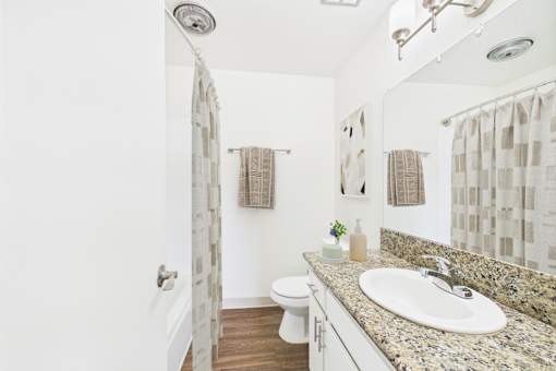 A bathroom with a granite countertop and a white sink.