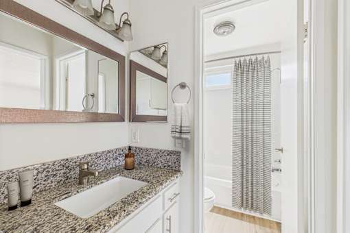 A bathroom with a marble counter top and a shower with a curtain.