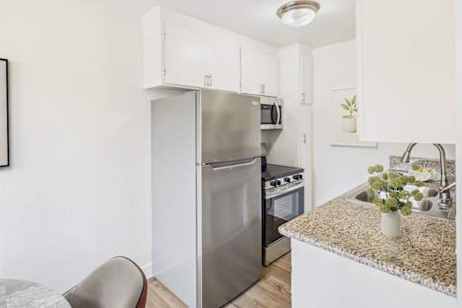 A kitchen with a refrigerator, oven, and sink.