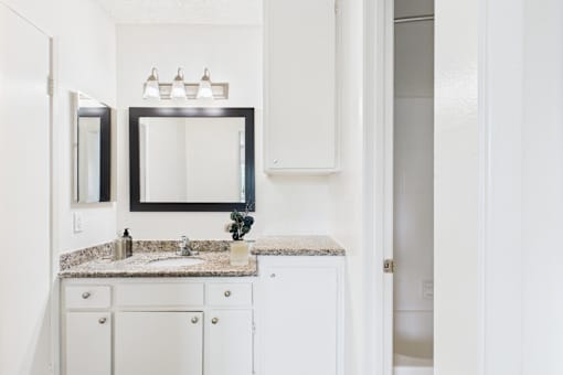 A bathroom with a sink, mirror, and cabinets.