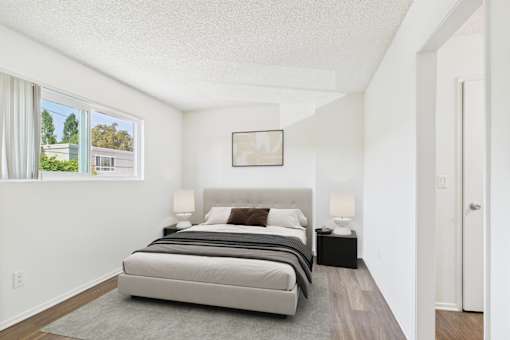 A bedroom with a large bed and a framed picture on the wall.