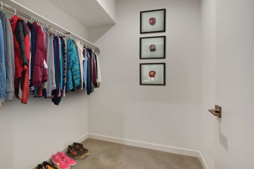 a walk in closet with clothes hanging on a rack and shoes on the floor
