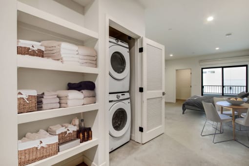 a washer and dryer in a laundry room with a table and chairs in the background