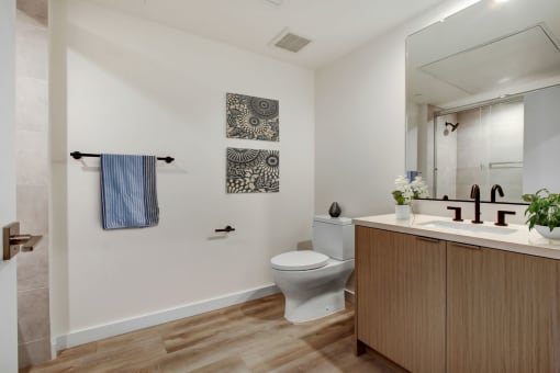 a bathroom with a toilet sink mirror and shower in a 555 waverly unit