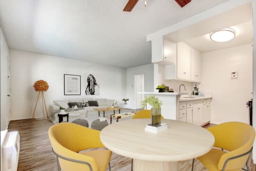 a living room and dining room with yellow chairs and a white kitchen